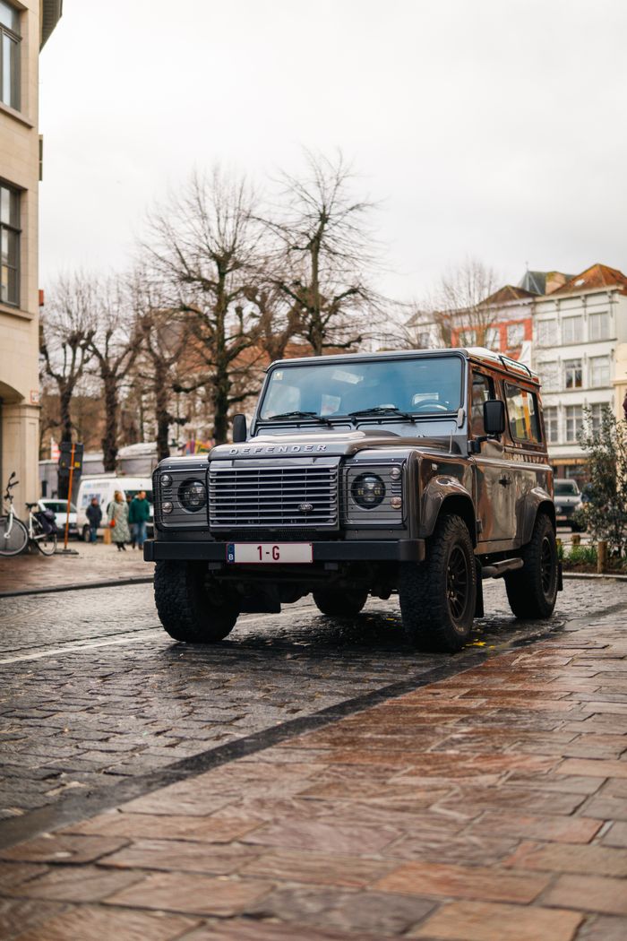 A rugged SUV parked on a cobblestone street in the historic city of Brugge, Belgium.
