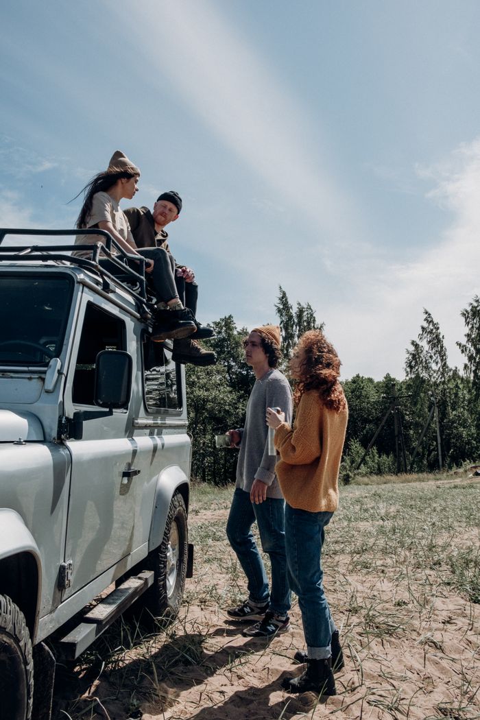 Group of friends enjoying a sunny day with an off-road vehicle, bonding outdoors in nature.